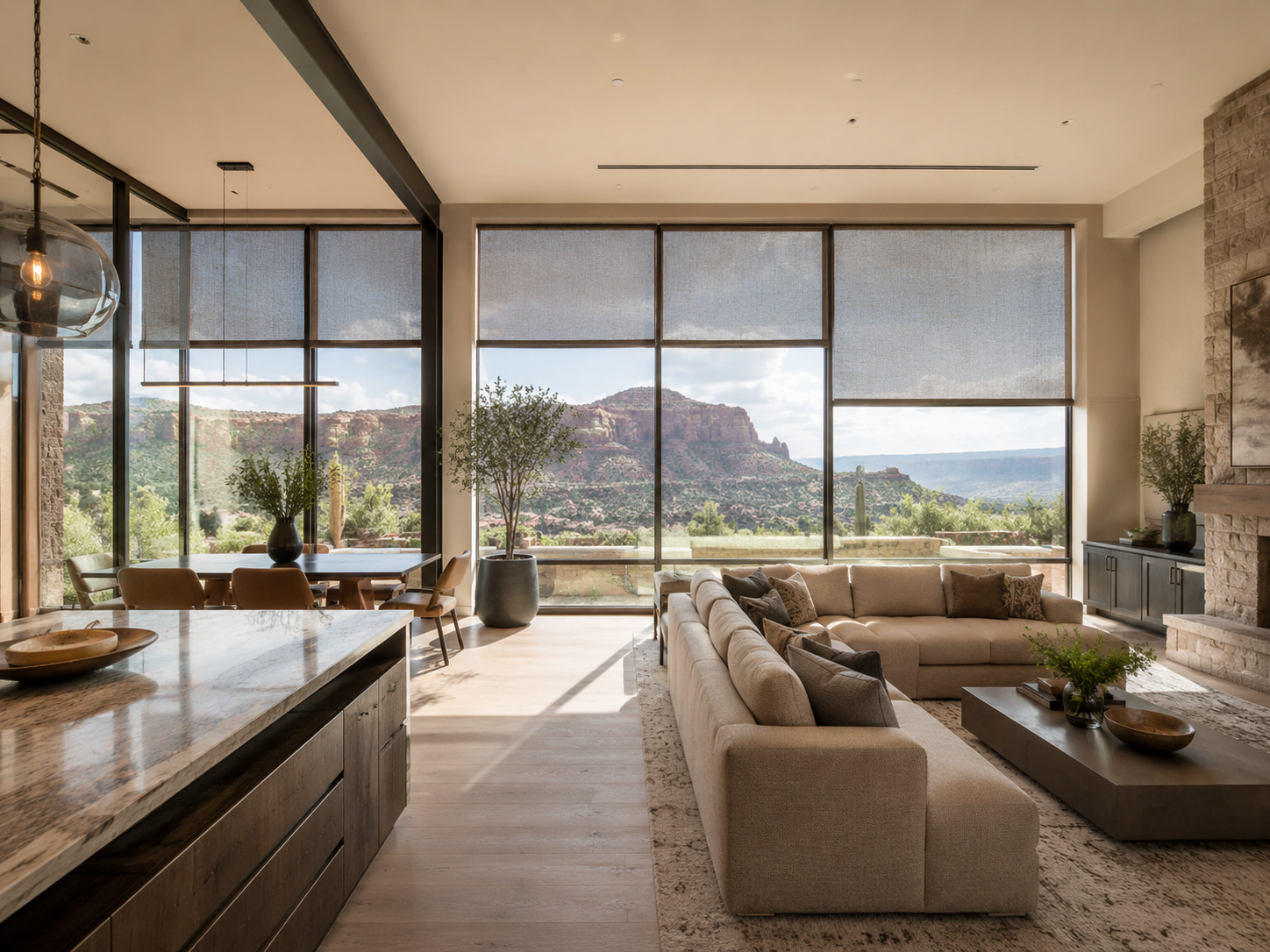 An open-plan living room with multiple roller shades filtering bright desert light.