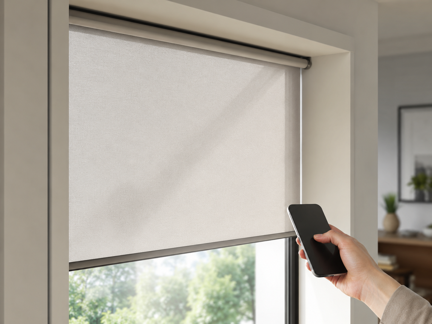 A motorized roller shade being controlled by smartphone beside a bright window.